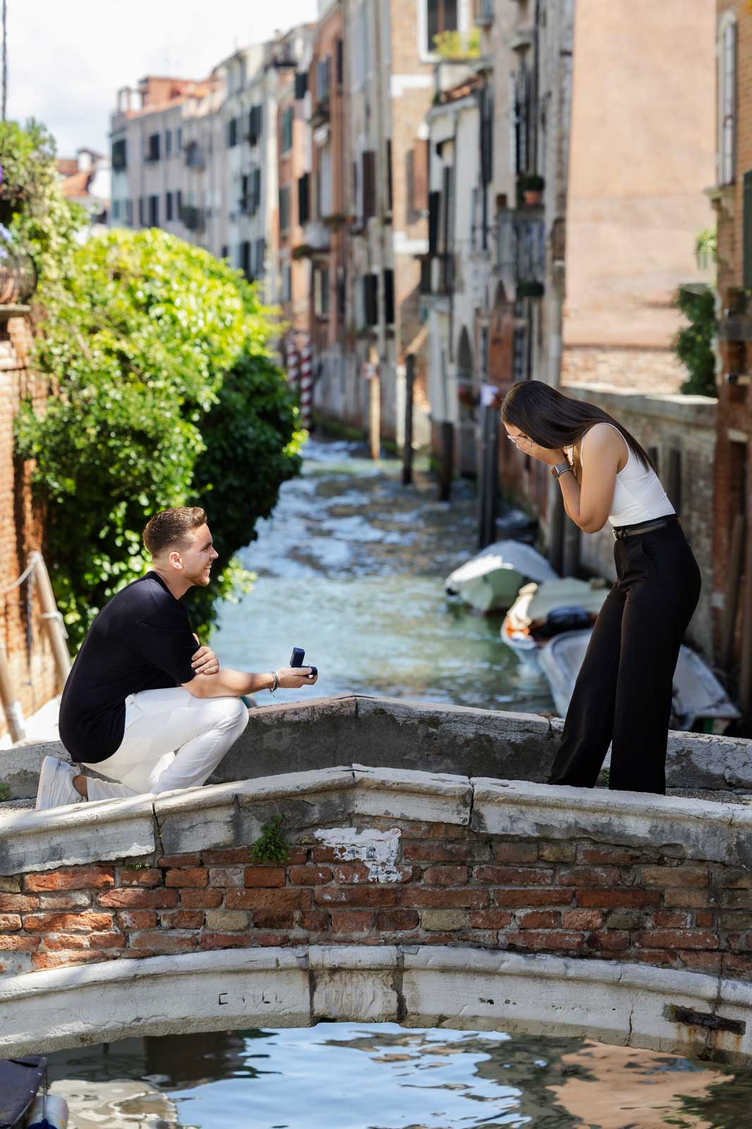 Man proposing on Ponte Chiodo in Venice while woman reacts emotionally