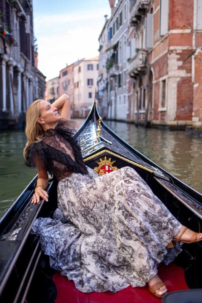 Woman sitting on a boat in a narrow inner canal in Venice with completely still water