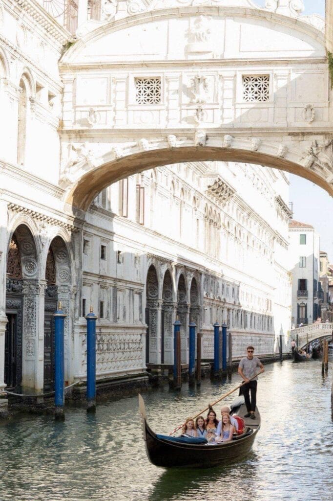 Family in a gondola passing under the Bridge of Sighs in Venice, photographed from the bank