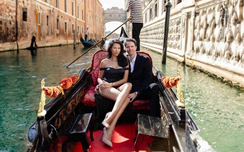 Couple photographed from the bow of a gondola with the Bridge of Sighs behind them in Venice