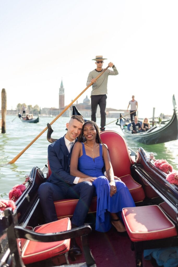 Couple in a gondola backlit by the sun with the island of San Giorgio behind them