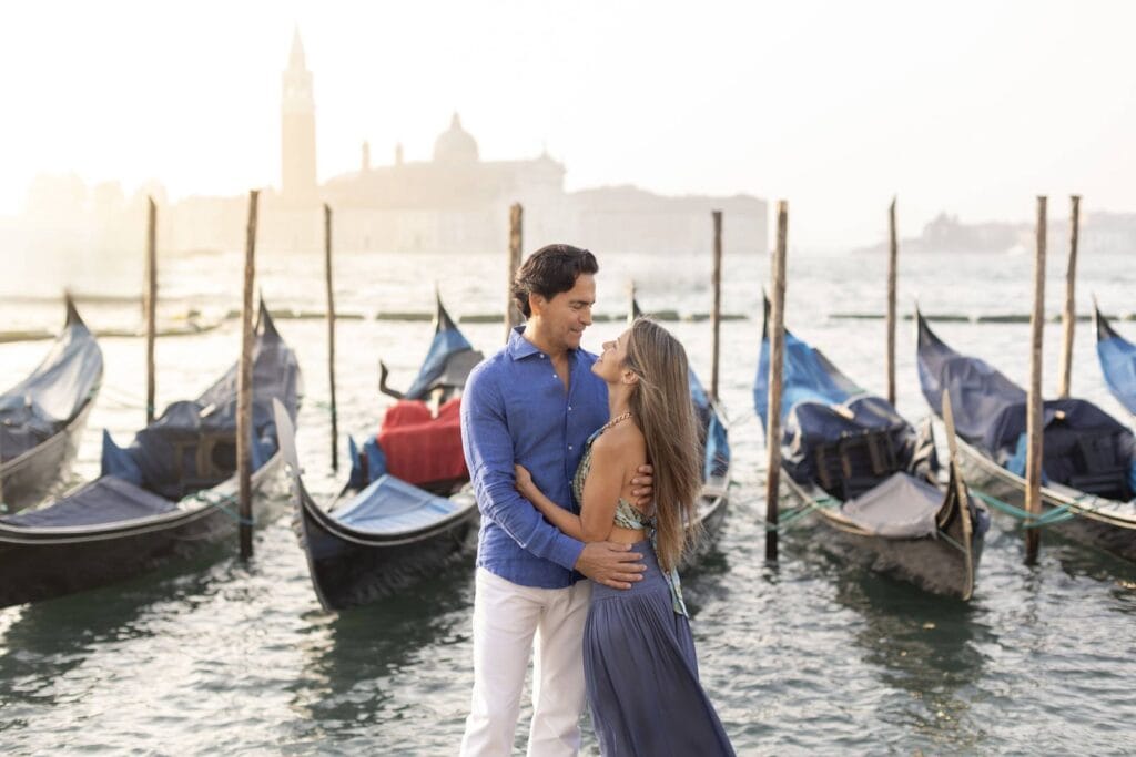 Man in a linen shirt and woman in a flowing dress at sunrise on an empty Venetian street in July