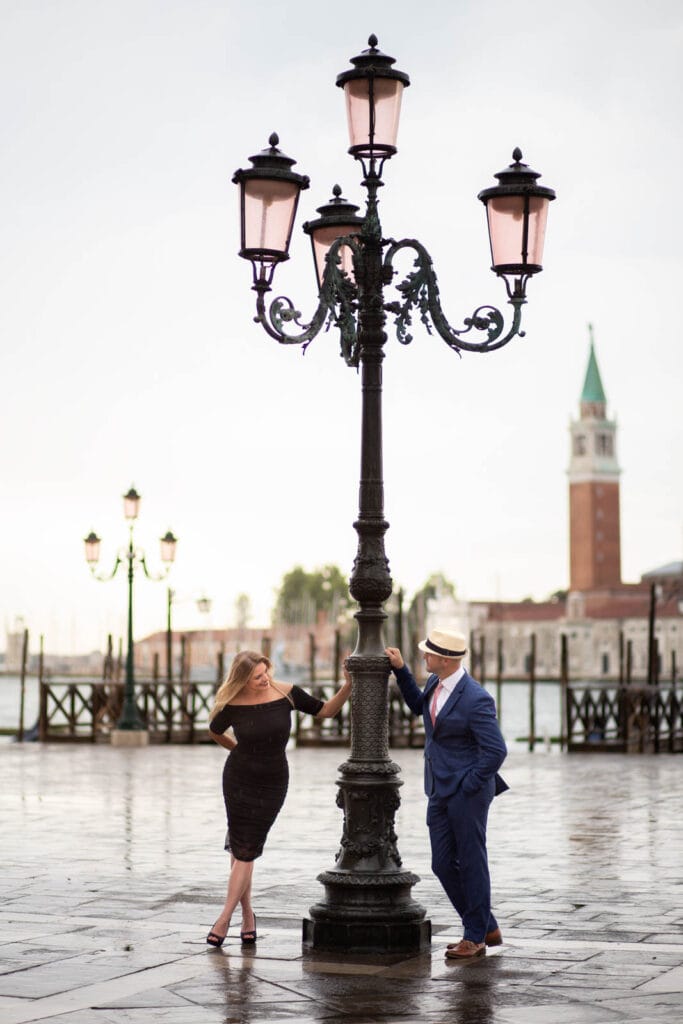 Couple in structured winter coats with morning mist and low sun behind them in Venice